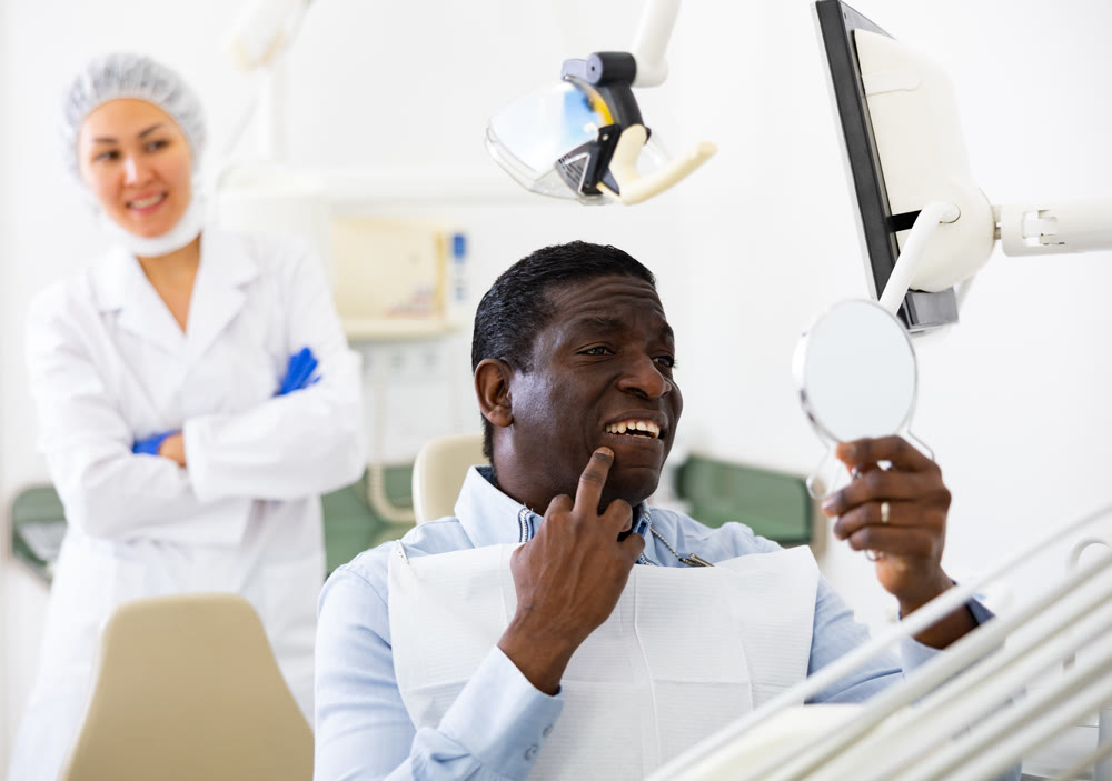Man looking in mirror to evaluate results of dental restoration procedure