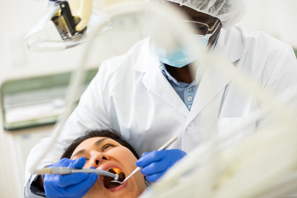 Male dentist using tools for tooth repairing on woman patient
