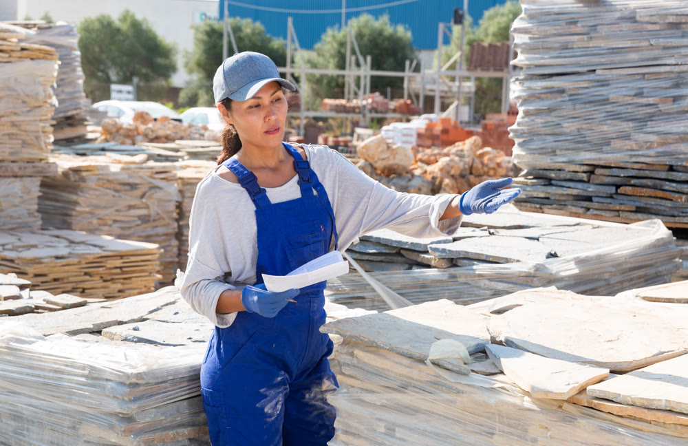 Manager of hardware store keeps records of natural stone tiles on open-air site