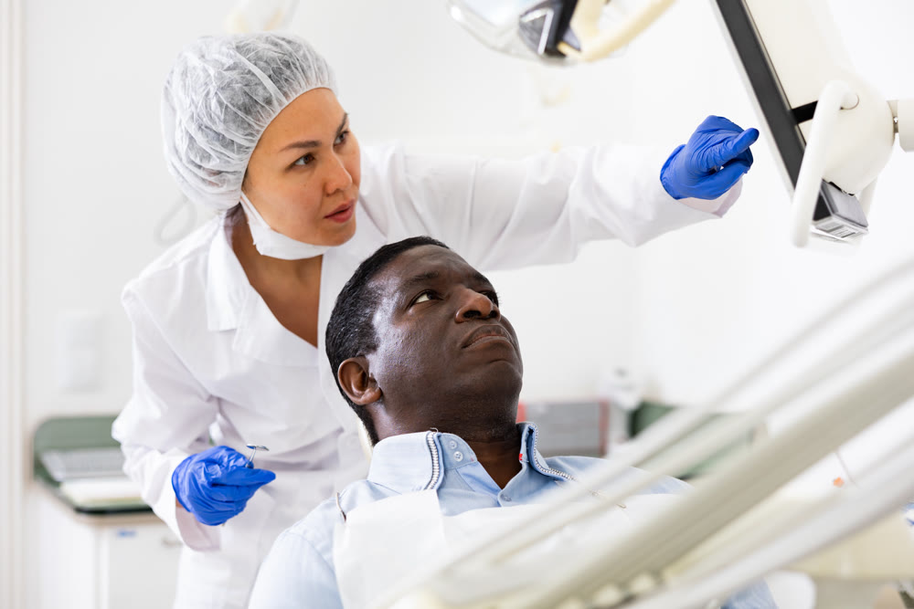Man patient and woman dentist looking at monitor during consultation