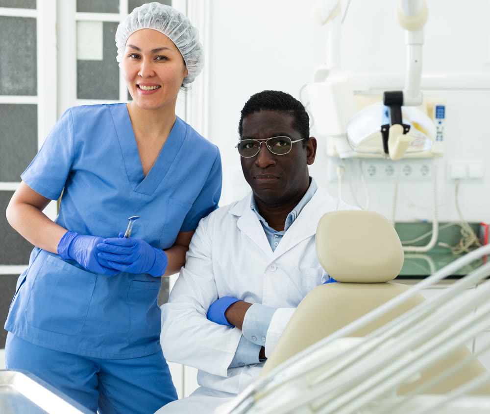Positive confident dentist with female assistant in dental office