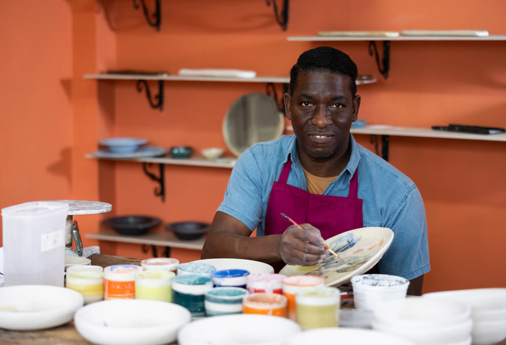 Man potter painting new ceramic plate