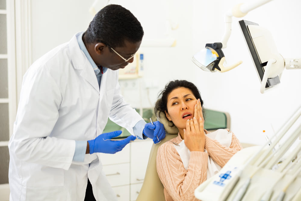 Asian woman with toothache sitting in chair at dentist appointment
