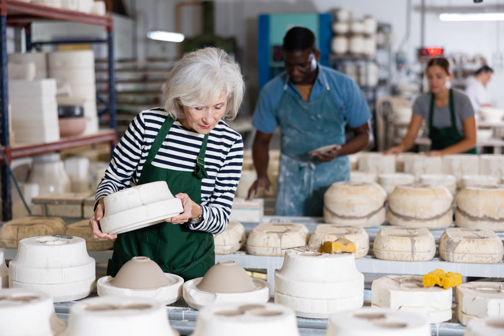 Elderly female worker removes half of the gypsum mold. Removal of the first part of clay mold