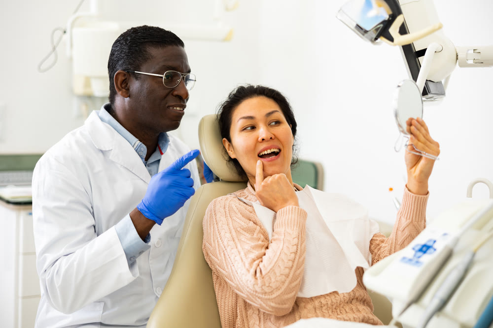 Satisfied dentist with female patient examining results of treatment