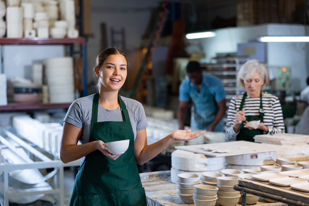 Female sculptor having ceramics in hands and standing in workroom
