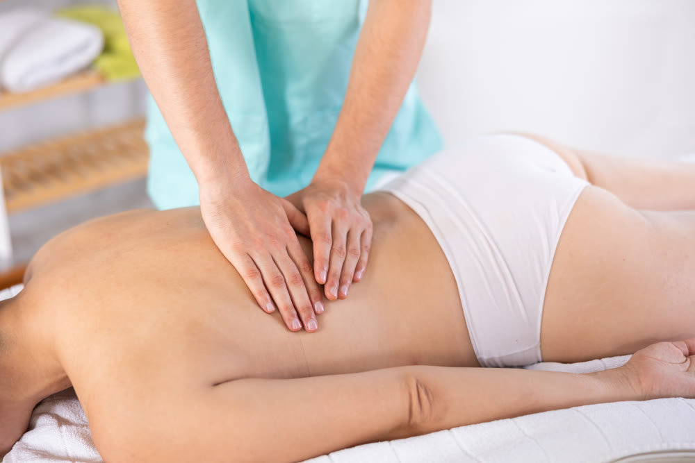 Masseur doing back massage to adult woman