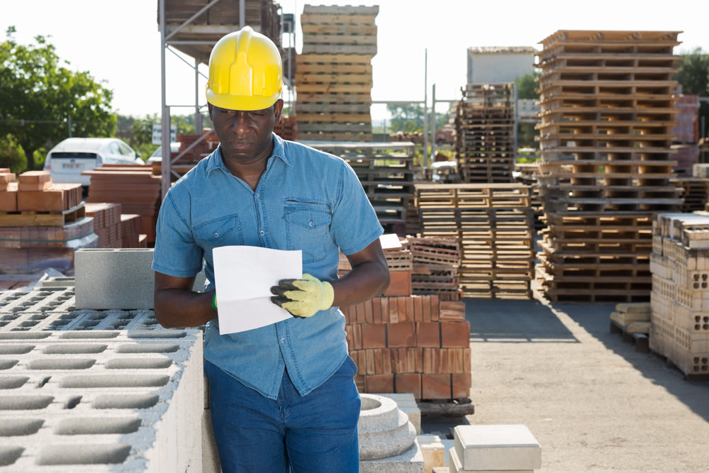 Worker filling documentation beside hollow block stack outdoors