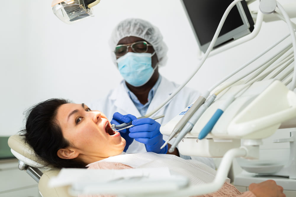 Orthodontist using tools and curing toothache of asian woman