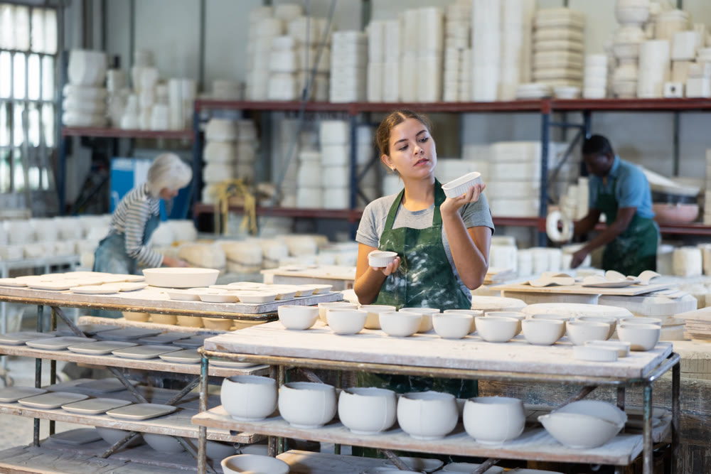 Young woman checks quality of pottery after being removed from plaster mold