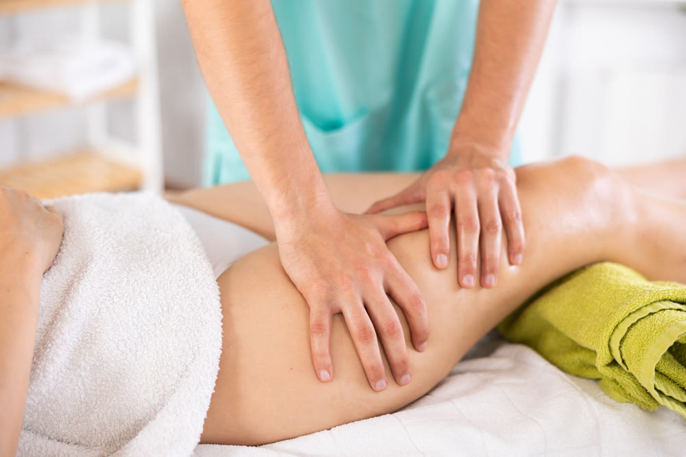 Close up of masseur hands doing leg massage of young girl