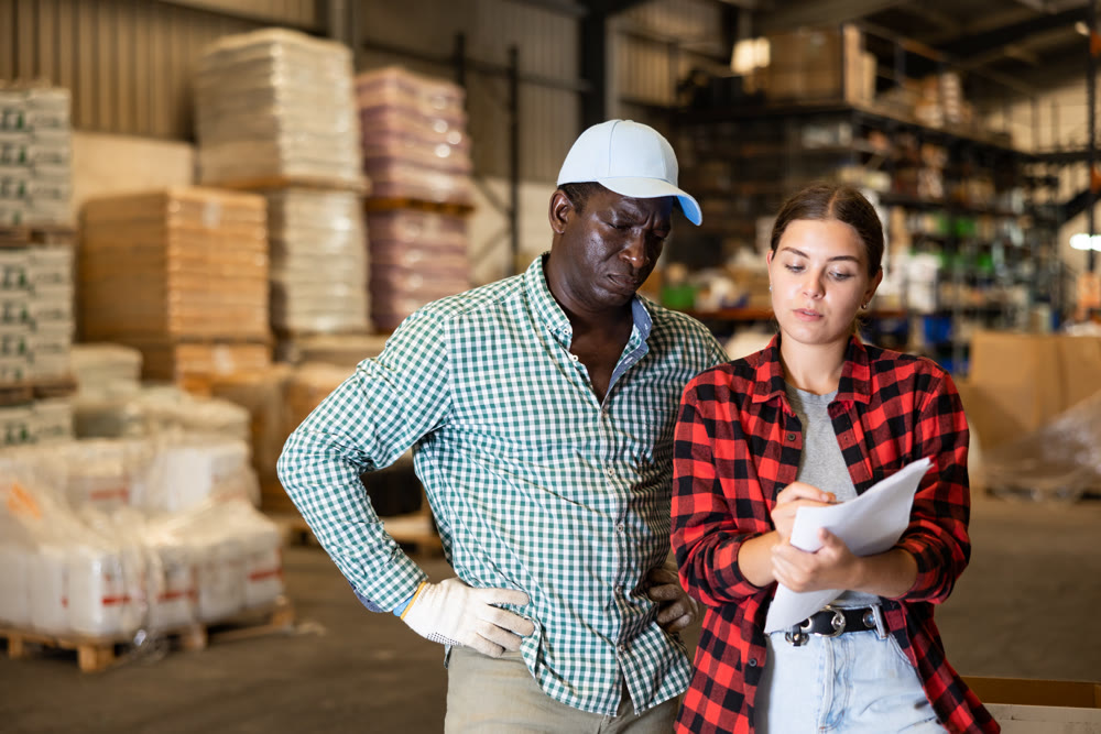 Woman and man discussing work details in storehouse