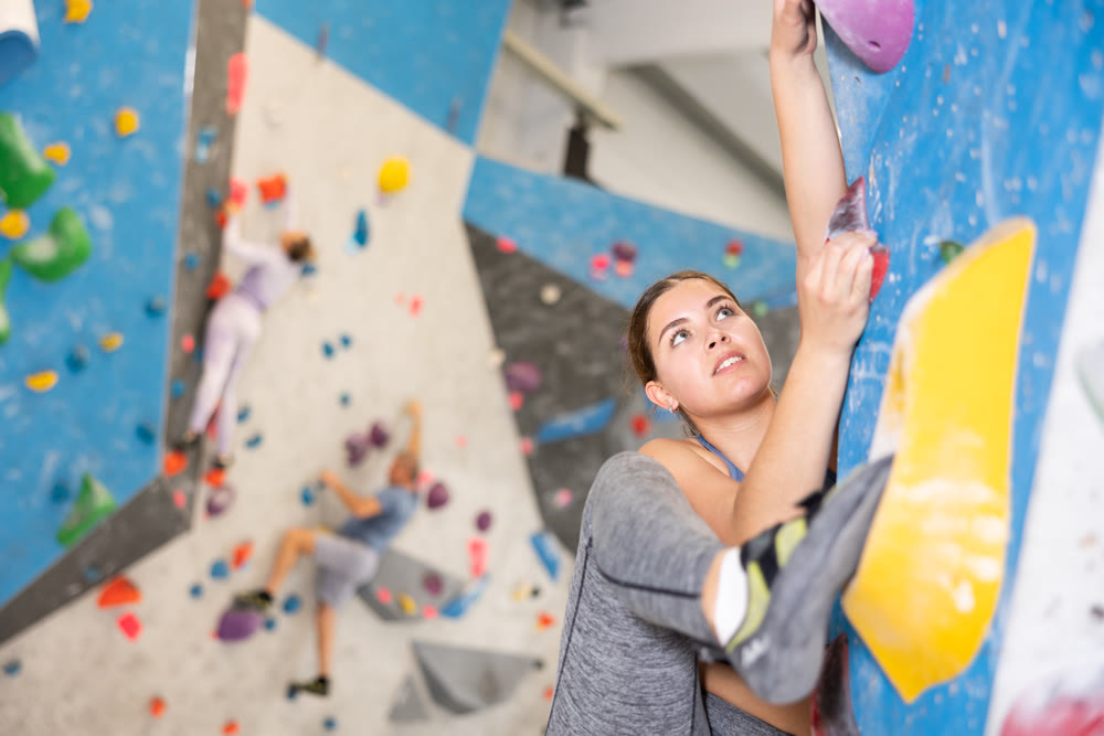 Young girl climbing without ropes and harnesses on bouldering wall