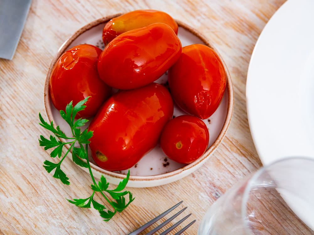 Red pickled tomatoes on plate close up. Preserve, fresh