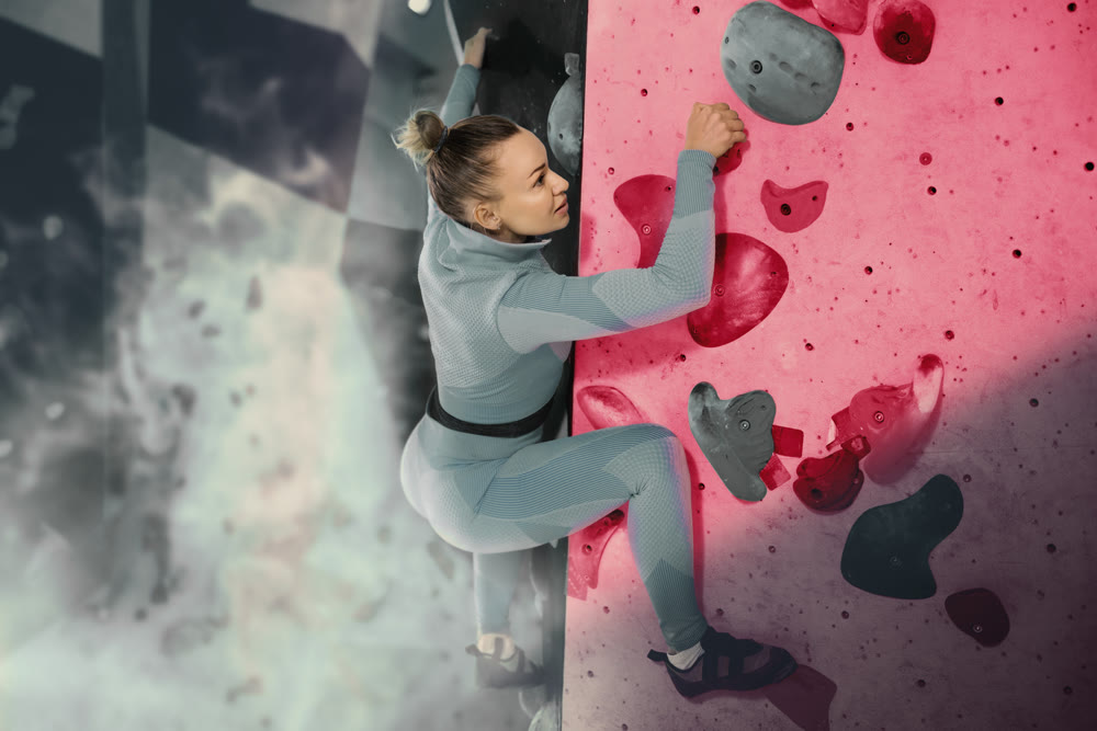 Young woman exercising on wall in climbing gym during bouldering training