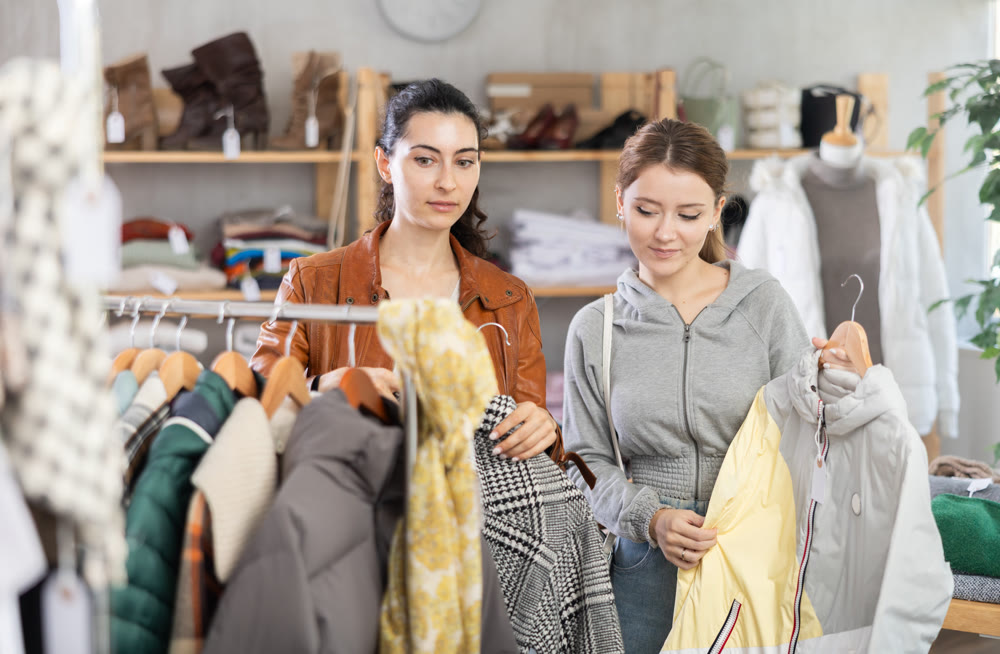 Two girls choose outerwear for the autumn winter season