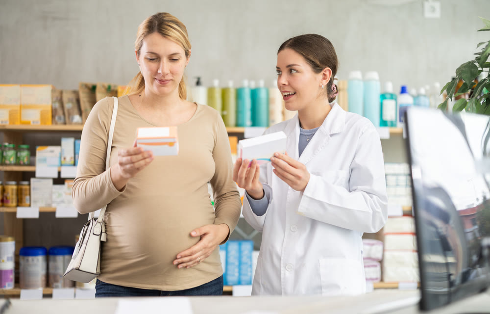 Woman pharmacist offering pills to pregnant woman