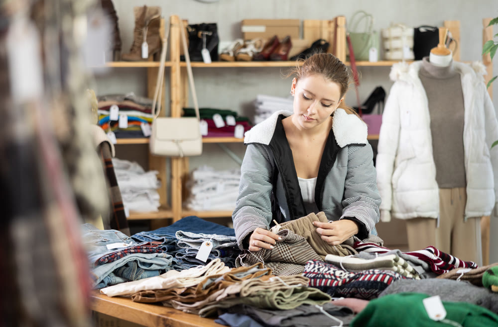 Young woman near showcase examine goods, buying trousers