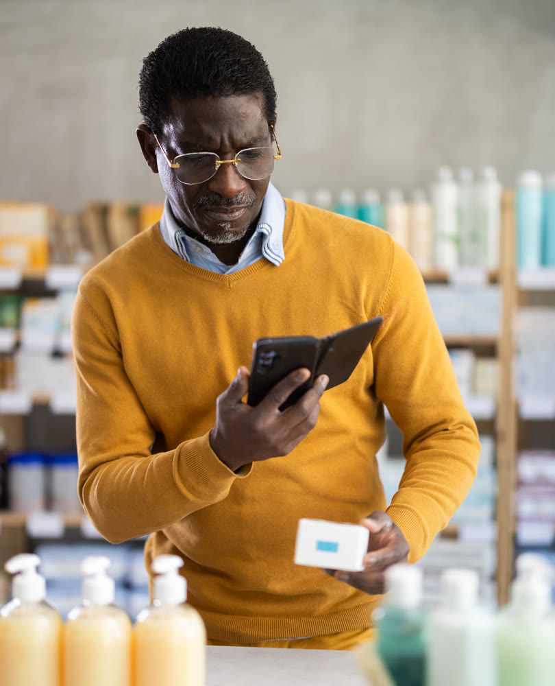 Man in glasses scans code on package of pills to check expiration date