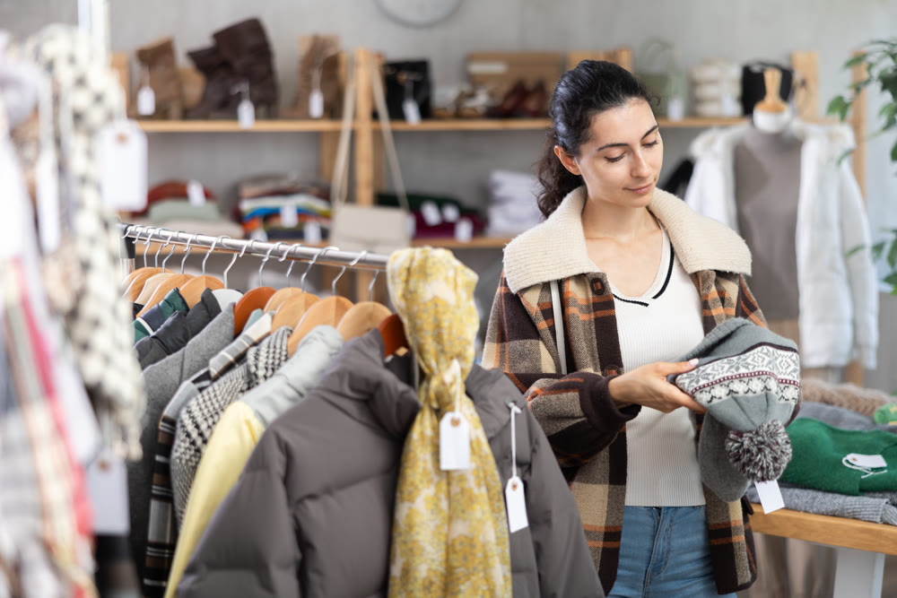 Happy woman chooses demi-season hat in clothing store