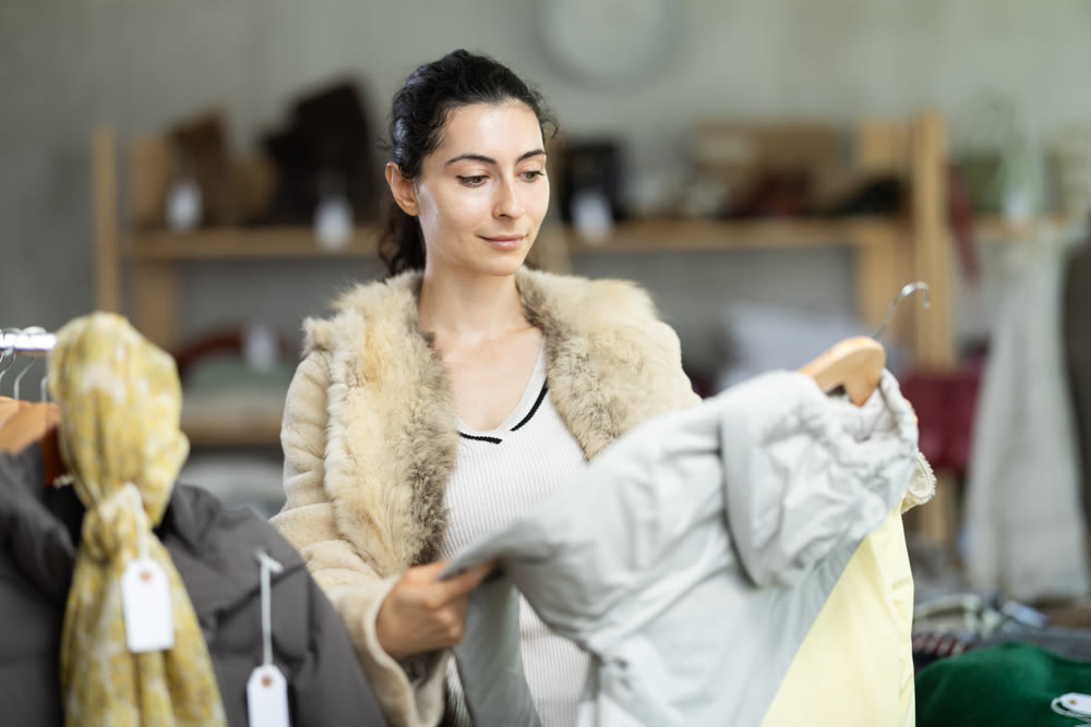 Female shopper chooses jacket in modern clothing store