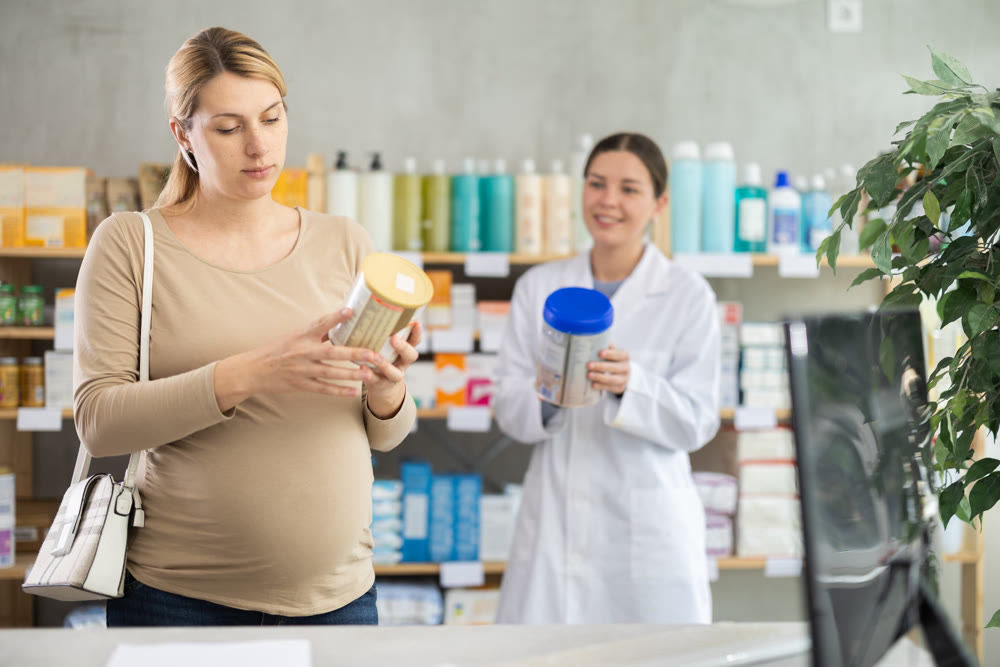 Pregnant woman choosing baby formula with help of pharmacist