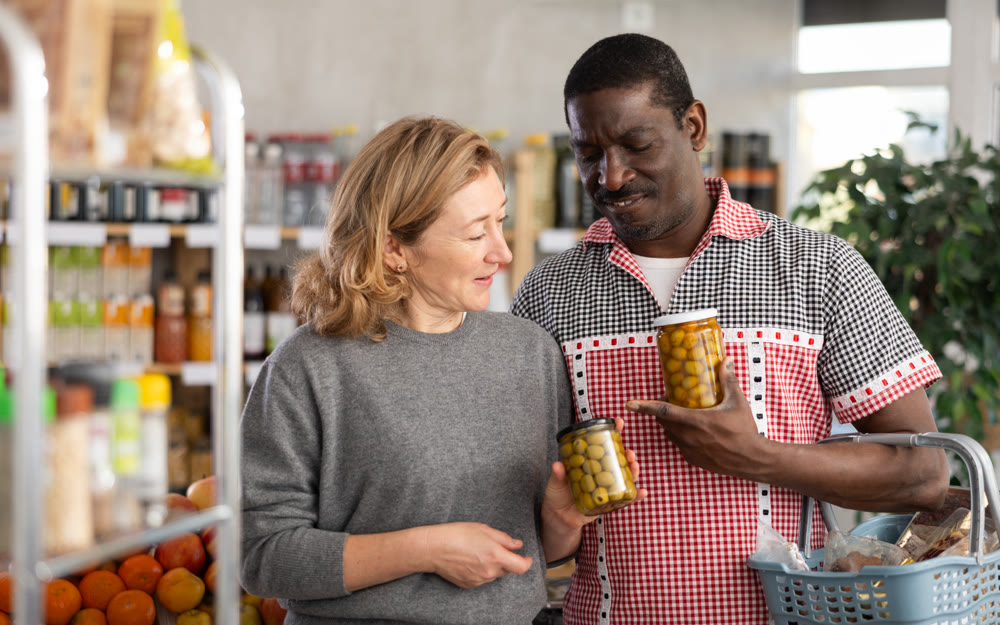 Husband and wife buy jars of pickled olives at grocery store
