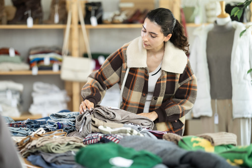 Female shopper chooses trousers in modern clothing store