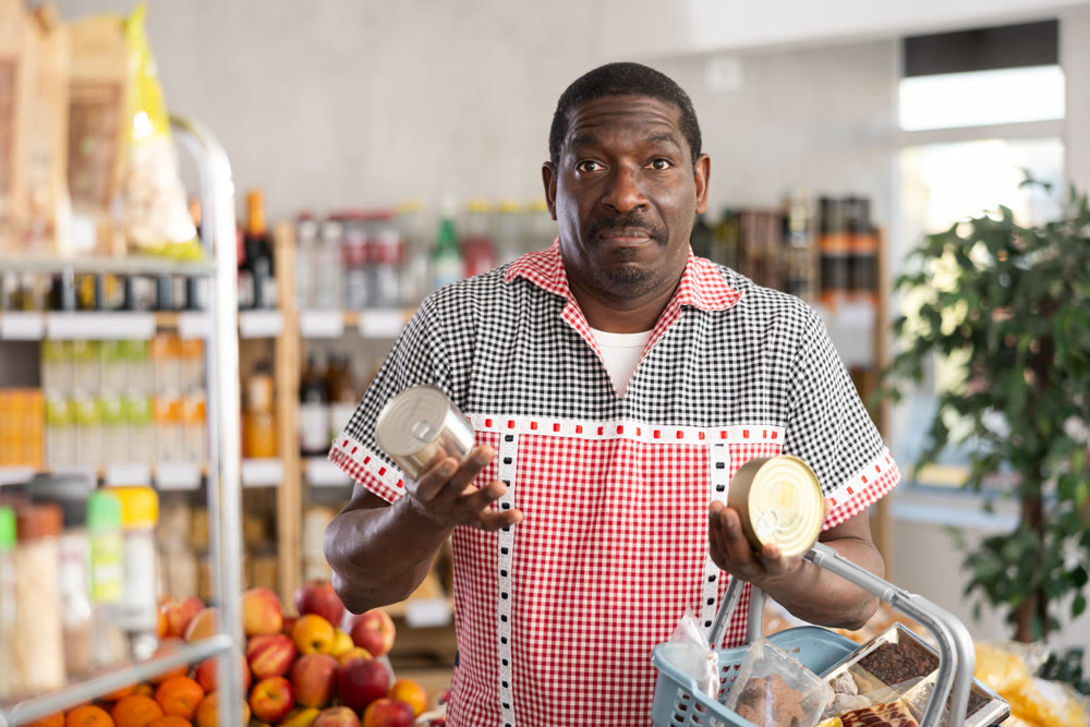 Adult man choosing canned food in grocery store