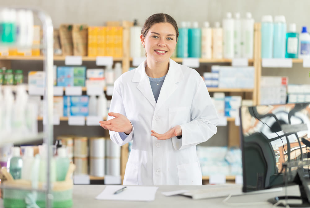 Young female pharmacist welcoming clients in chemist's shop