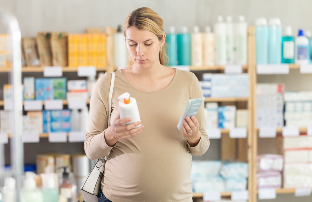 Pregnant woman choosing cream in drugstore