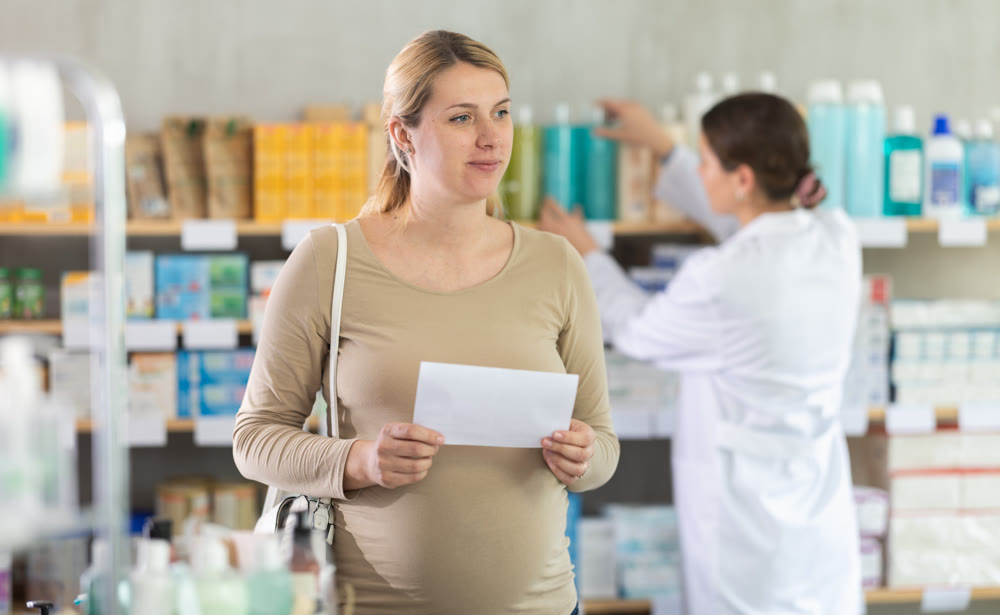 Pregnant woman with prescription looking for items in pharmacy