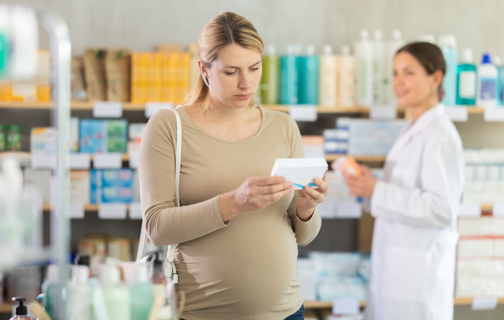 Pharmacist helping pregnant woman choose prenatal vitamins