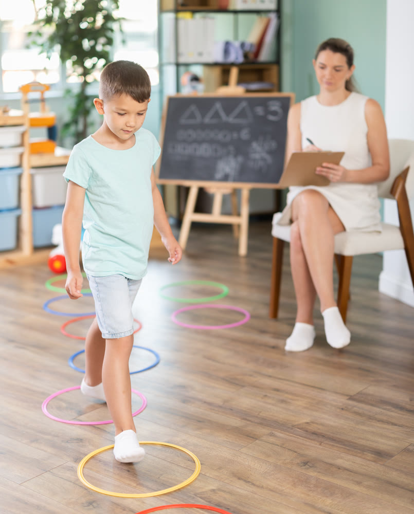 Boy performs exercises and steps into center of circle outlined by plastic ring