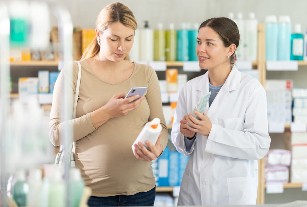 Expecting woman scanning QR code on stretch mark cream in pharmacy