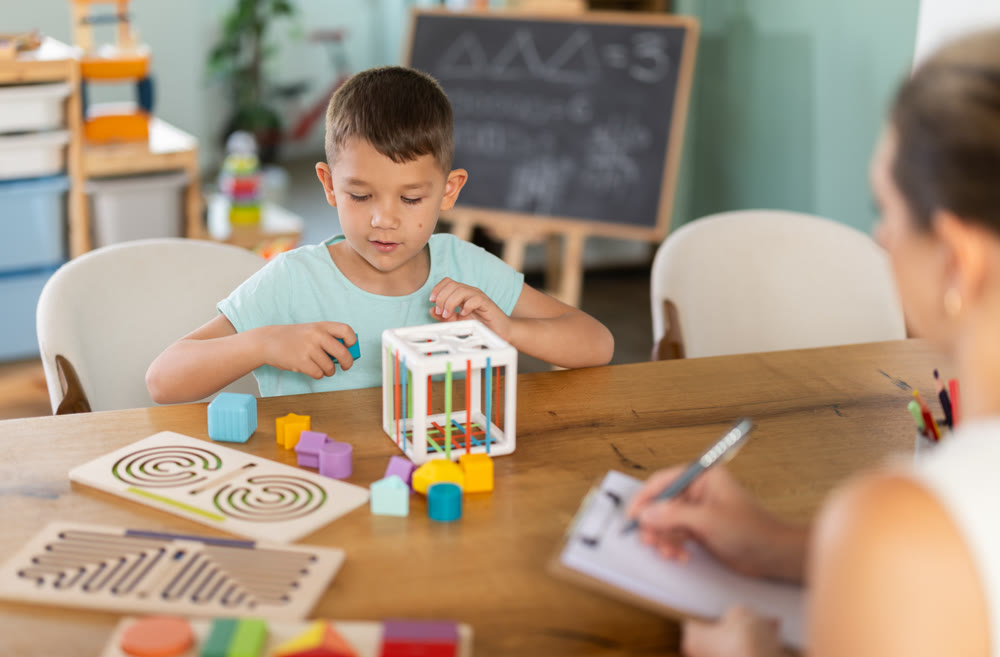 Child psychologist conducts test - asks boy to insert figures of different shapes and colors into cube