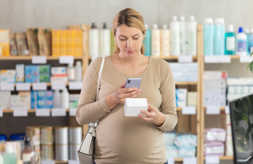 Pregnant woman in pharmacy scans QR code on vitamin pills product
