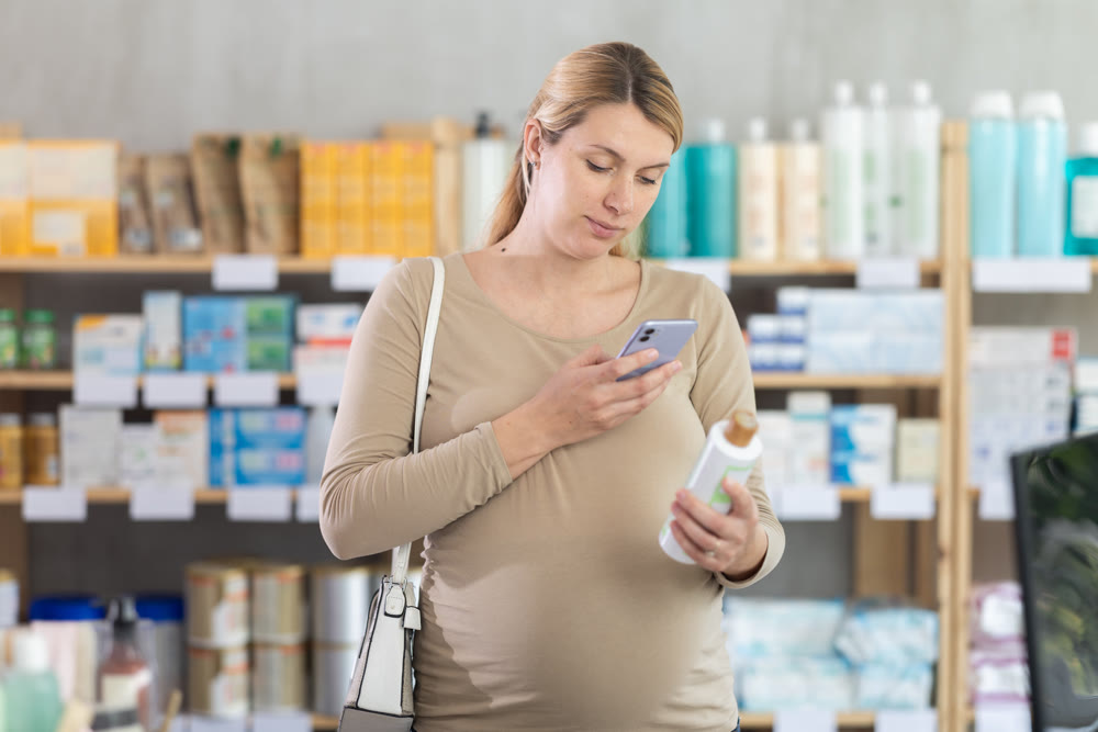 Pregnant woman in pharmacy scans QR code on hair loss shampoo product