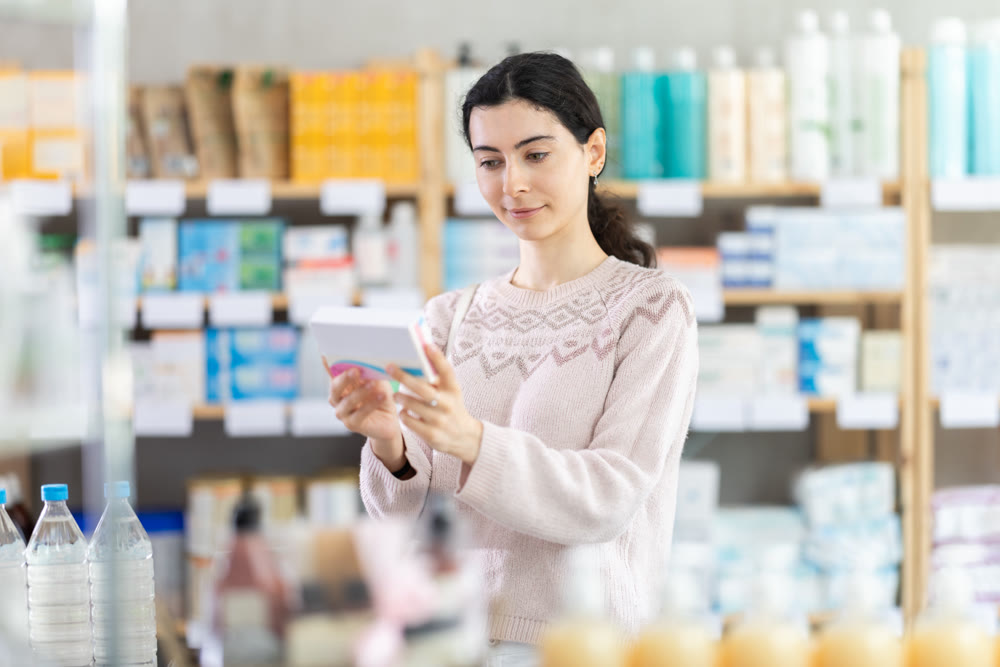 Young woman chooses pills at pharmacy