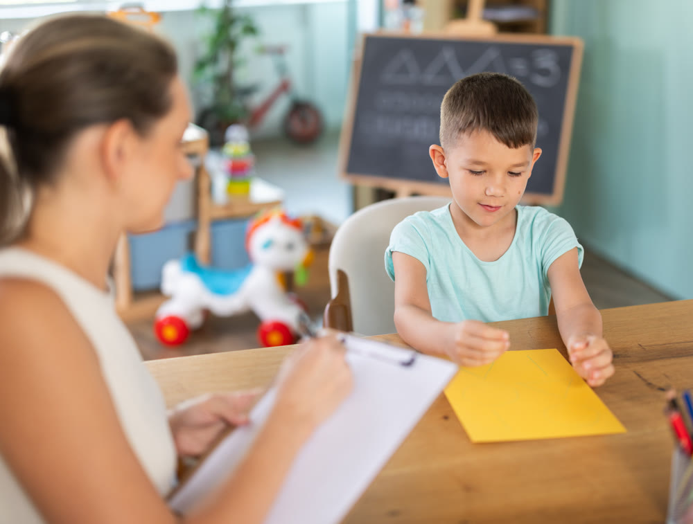 Little boy training bilateral coordination with palms near psychologist