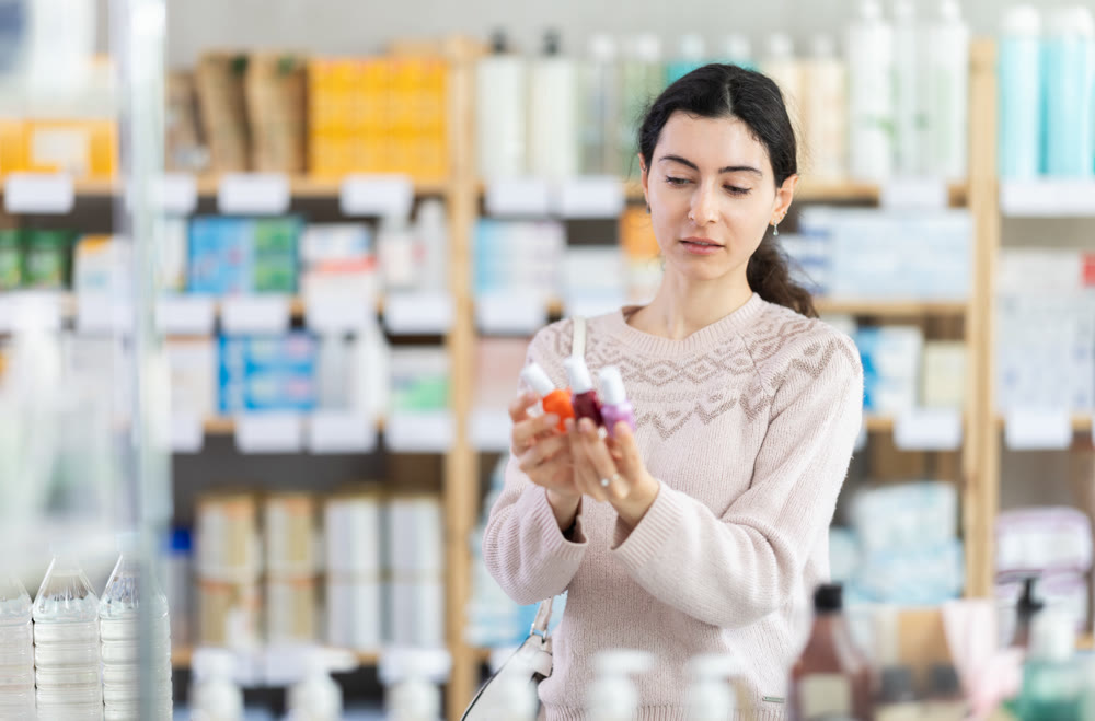 Young woman chooses nail polish at pharmacy