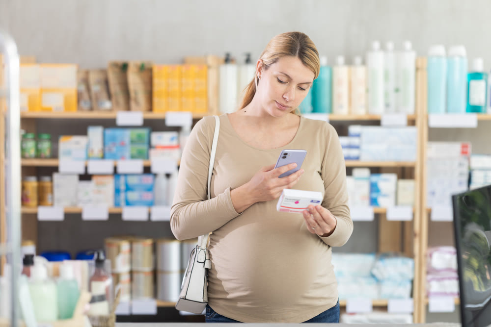 Pregnant woman customer scanning QR-code on pills box