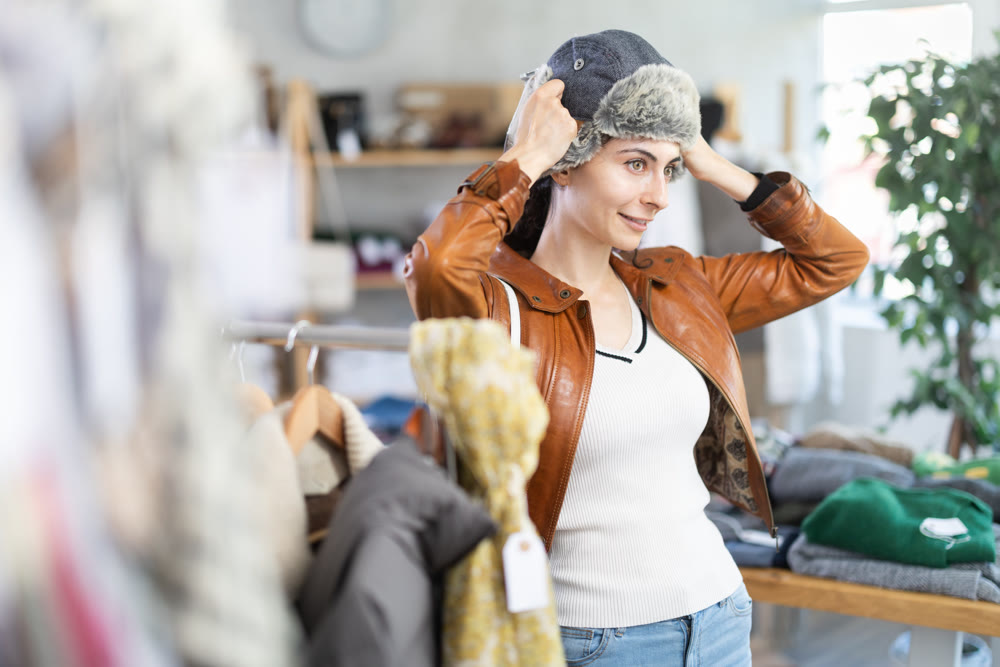 Young woman chooses fur hat in clothing store