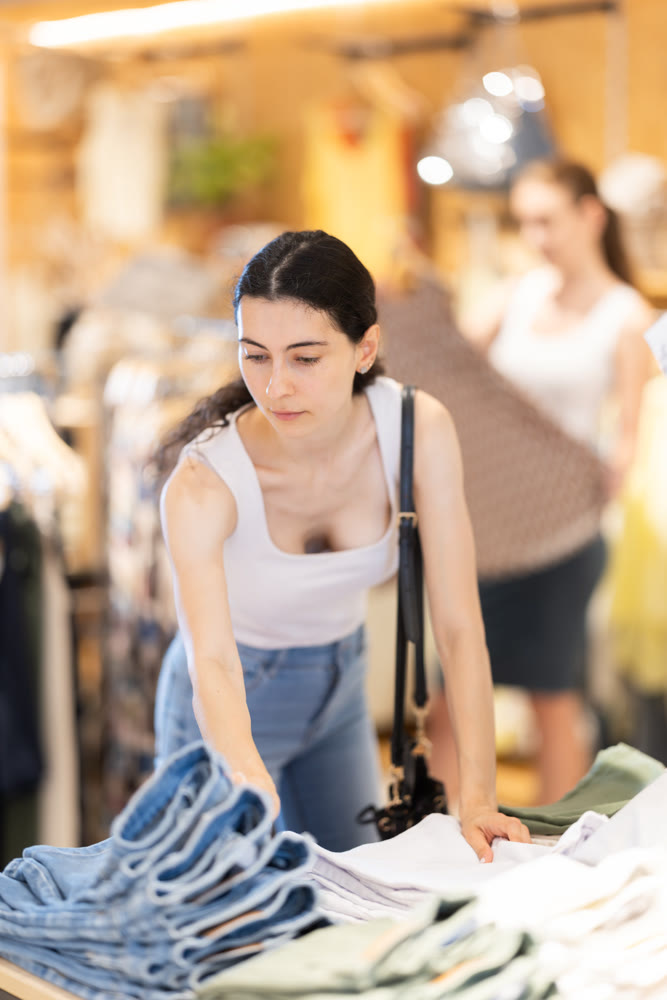 Young woman choosing denim shorts in clothing store