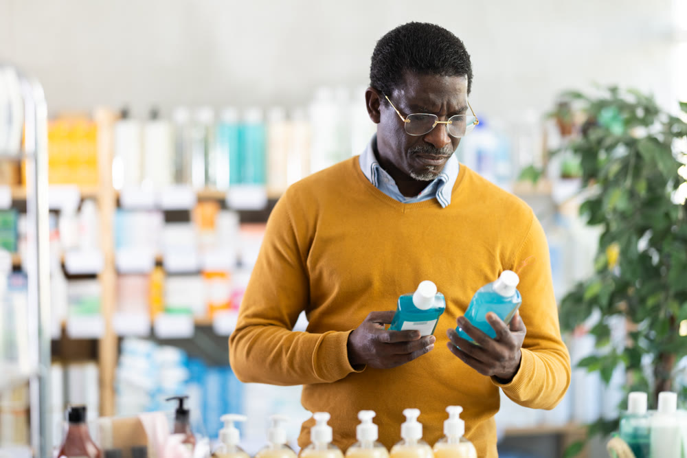 African American man choosing mouthwash at pharmacy
