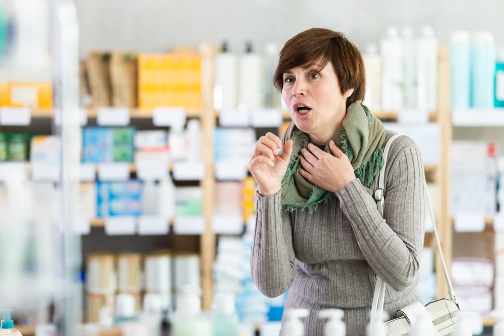 Woman suffering from severe cough in drugstore