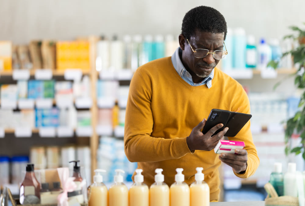 Man in glasses scans code on package of pills to check expiration date