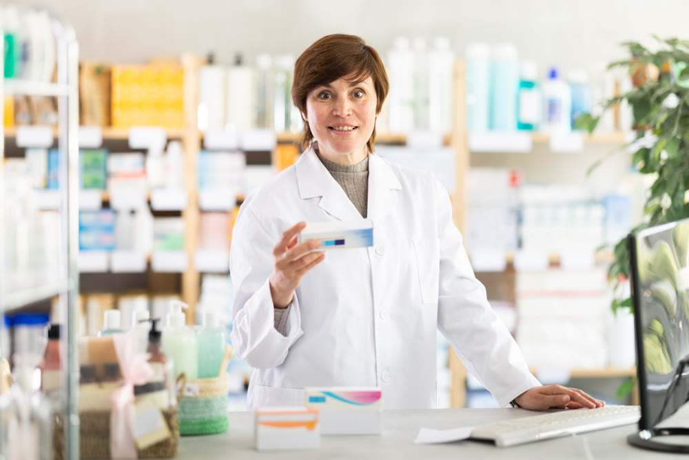 Female pharmacist recommending ointment at pharmacy counter