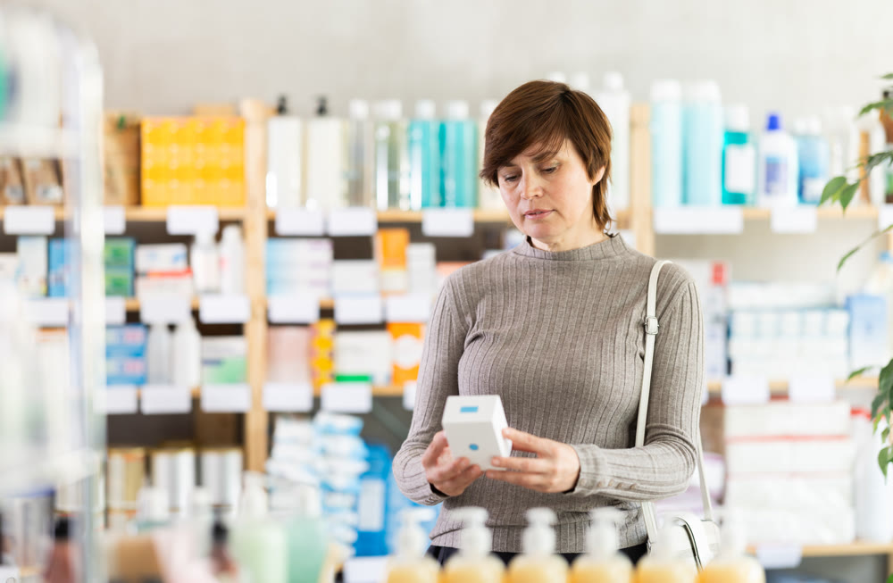 Female customer checking box of pills in pharmacy