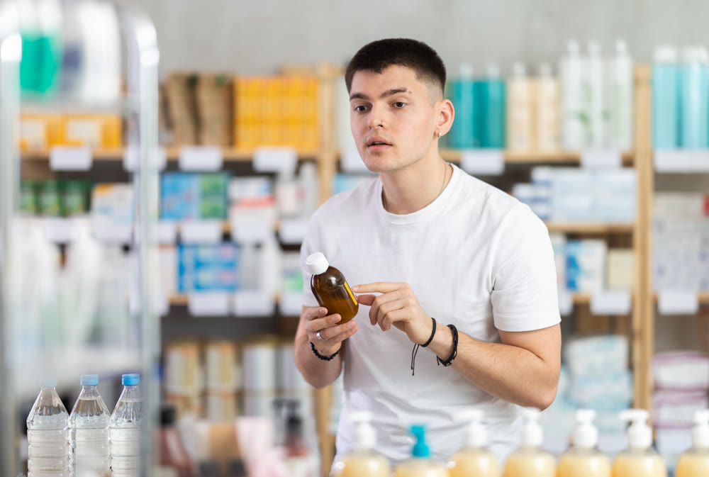 man chooses cough syrup in a pharmacy